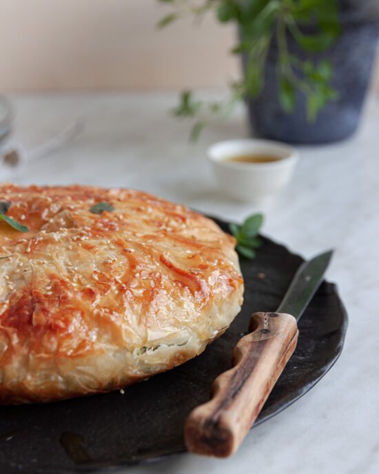 Cijela spanakopita sa špinatom na tanjuru uz nož