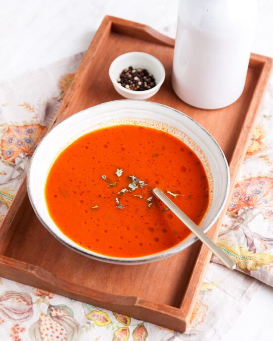 Tanjur juhe od pomidora s mesnim temeljcem poslužena u bijelom tanjuru na drvenom pladnju