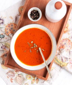 Tanjur juhe od pomidora s mesnim temeljcem poslužena u bijelom tanjuru na drvenom pladnju