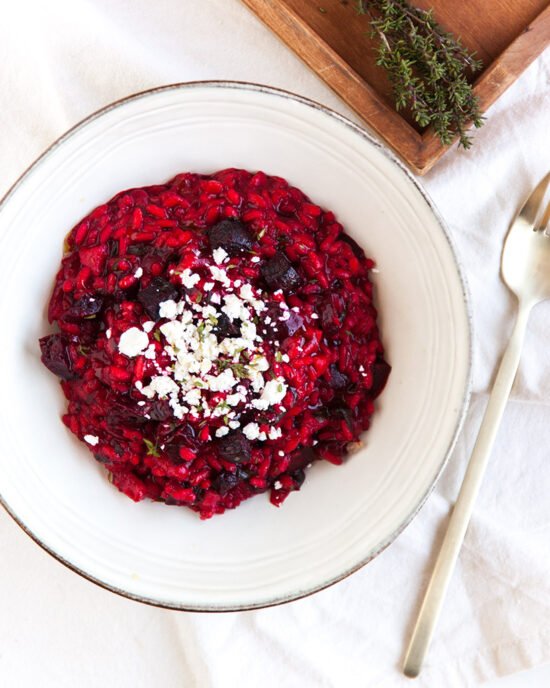 Rozi kremasti rižoto posipan feta sirom u dubokom tanjuru.