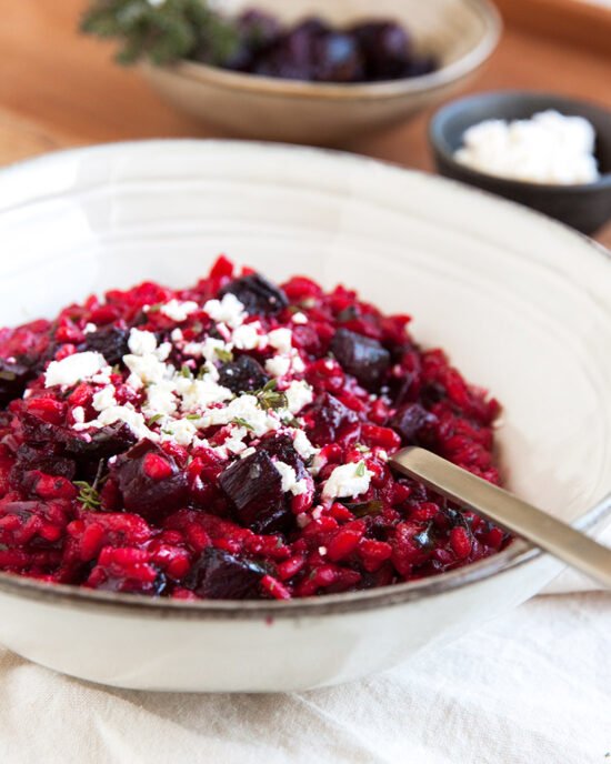 Rozi kremasti rižoto posipan feta sirom u dubokom tanjuru.